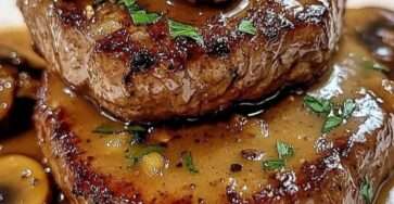 Steaks de bœuf poêlés nappés d’une sauce crémeuse aux champignons, présentés dans une assiette avec persil frais et texture dorée.
